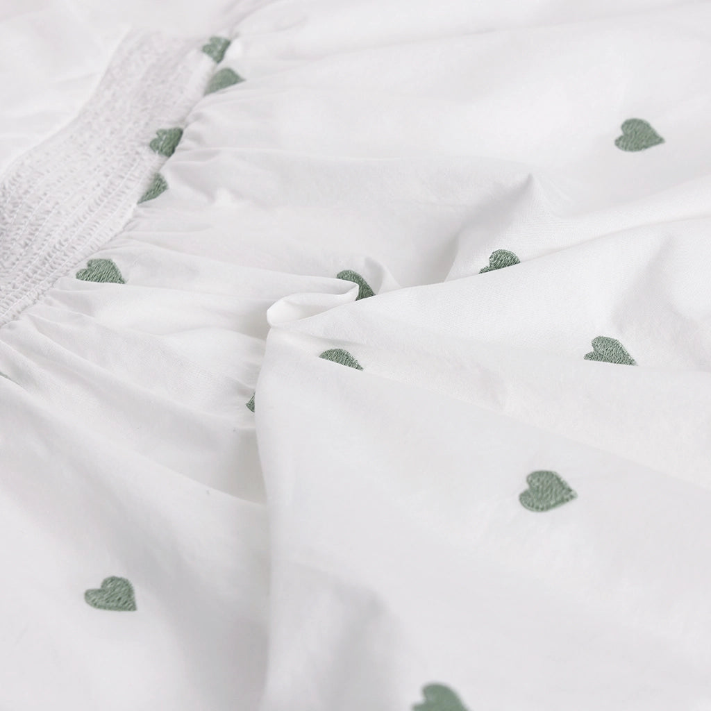 Close-up of white fabric with green heart patterns