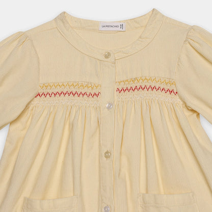 Yellow dress with smocked details on a white background