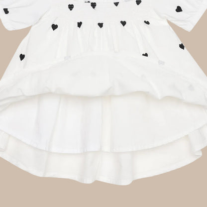 White dress with black heart patterns on a white background