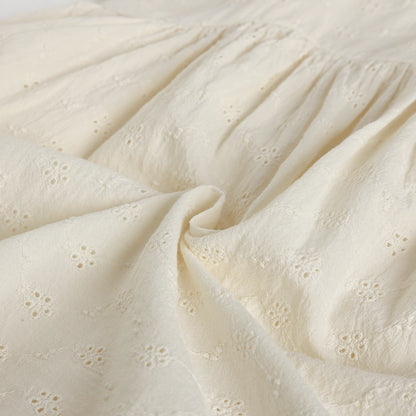 Close-up of textured beige fabric with floral eyelet pattern