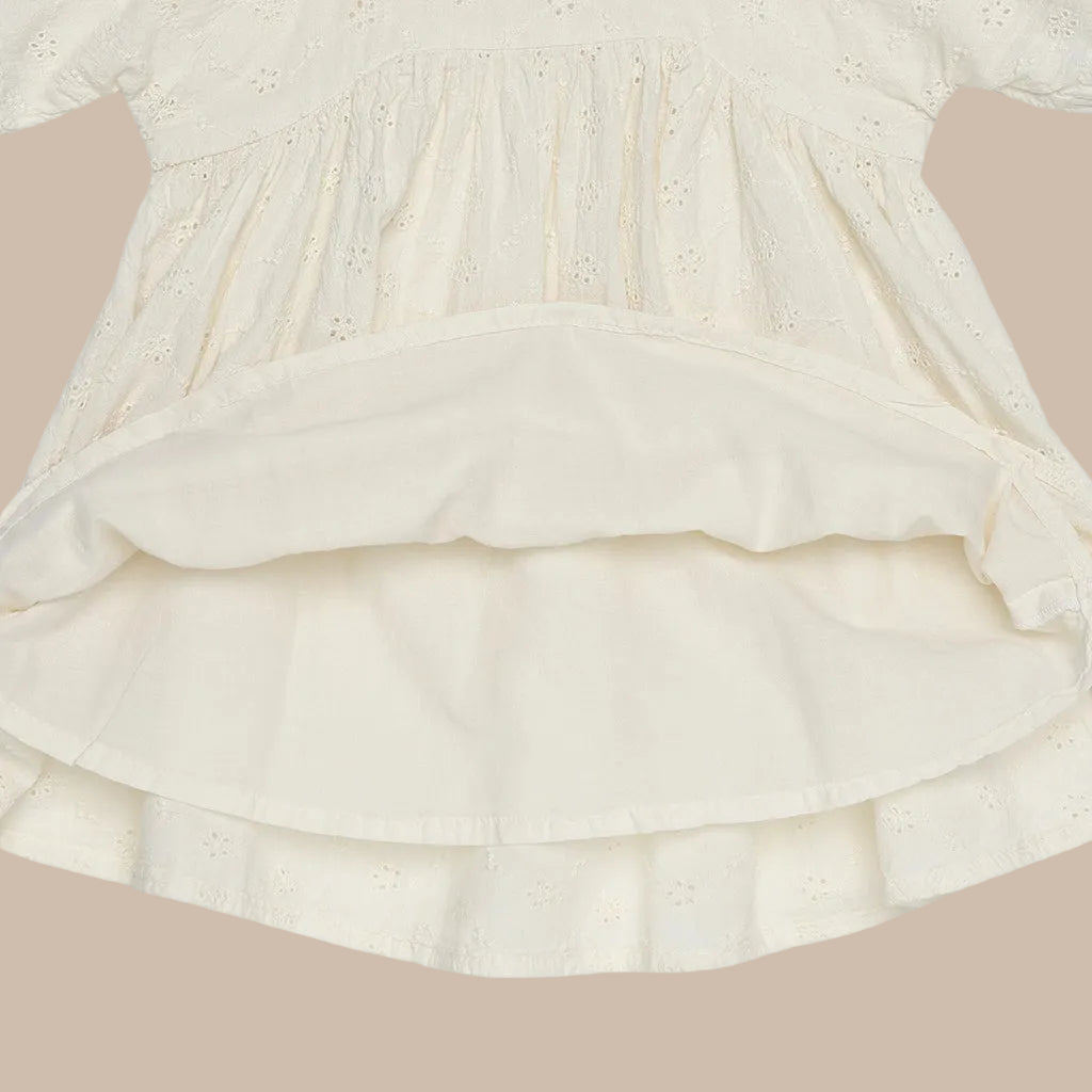 Close-up of a cream-colored dress with ruffled layers on a white background