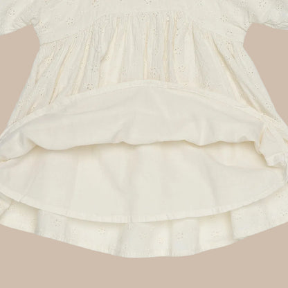 Close-up of a cream-colored dress with ruffled layers on a white background
