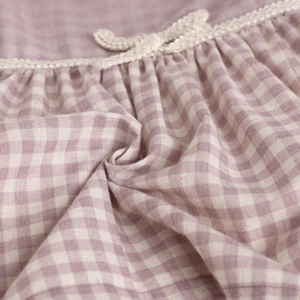 Close-up of a purple and white checkered fabric with lace trim.