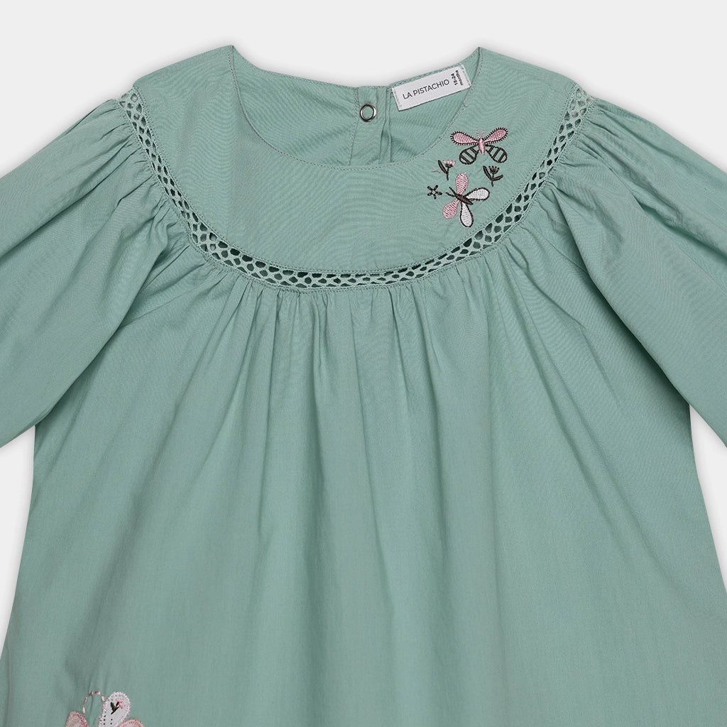 Green dress with embroidered details on a white background