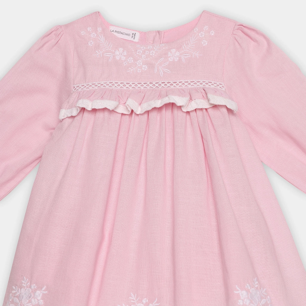 Pink dress with white floral embroidery on a light gray background