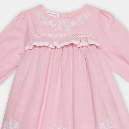 Pink dress with white floral embroidery on a light gray background