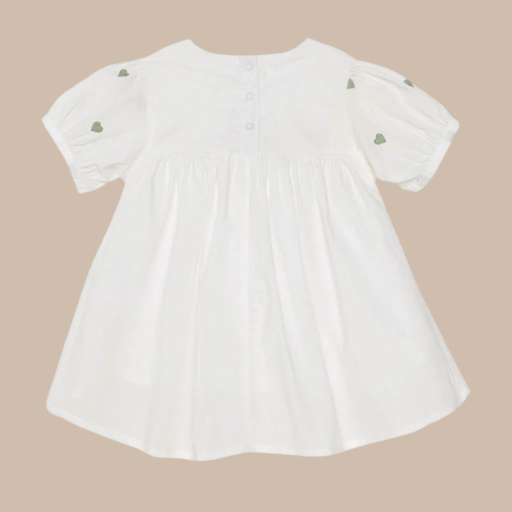 White baby dress with green heart details on a white background