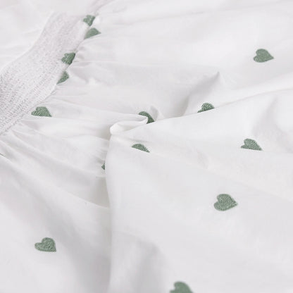 Close-up of white fabric with green heart patterns