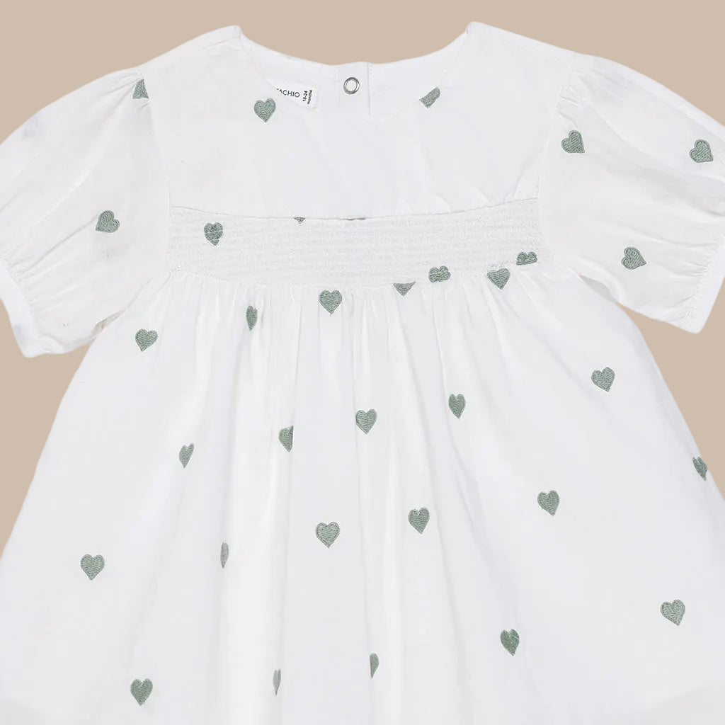 White dress with green heart patterns on a white background