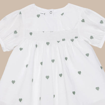 White dress with green heart patterns on a white background