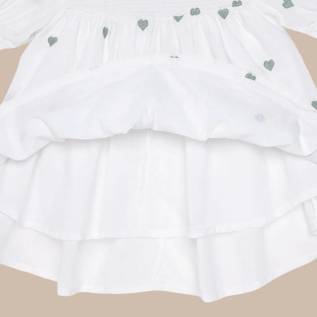 White ruffled fabric with small green heart patterns on a white background
