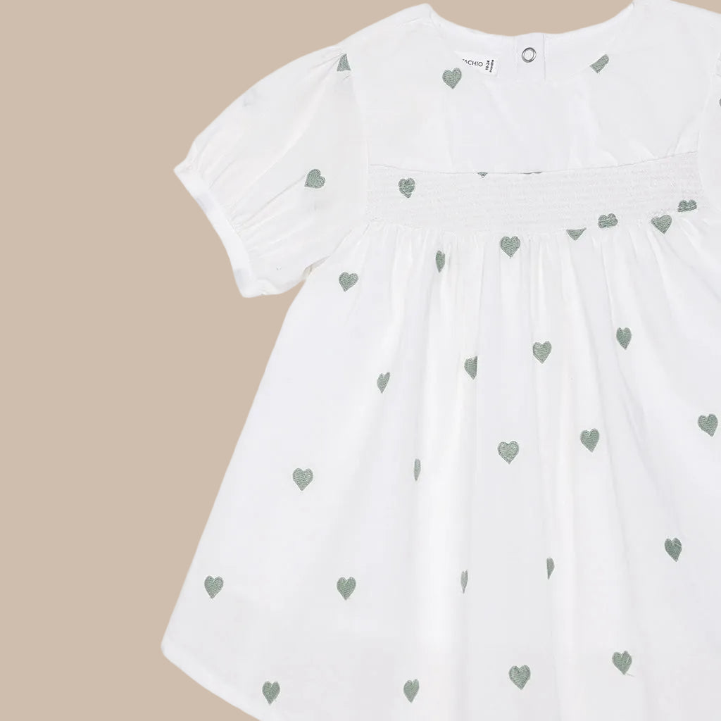 White dress with green heart patterns on a white background