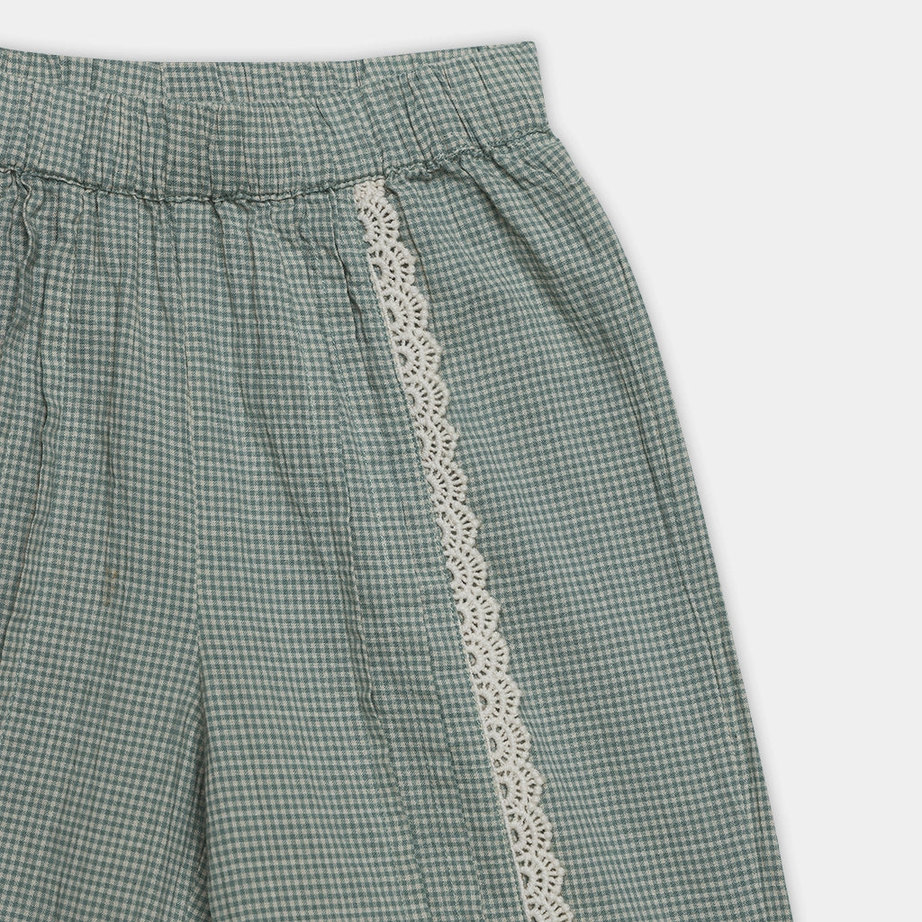 Green checkered pants with lace trim on a white background