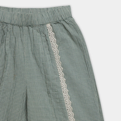 Green checkered pants with lace trim on a white background