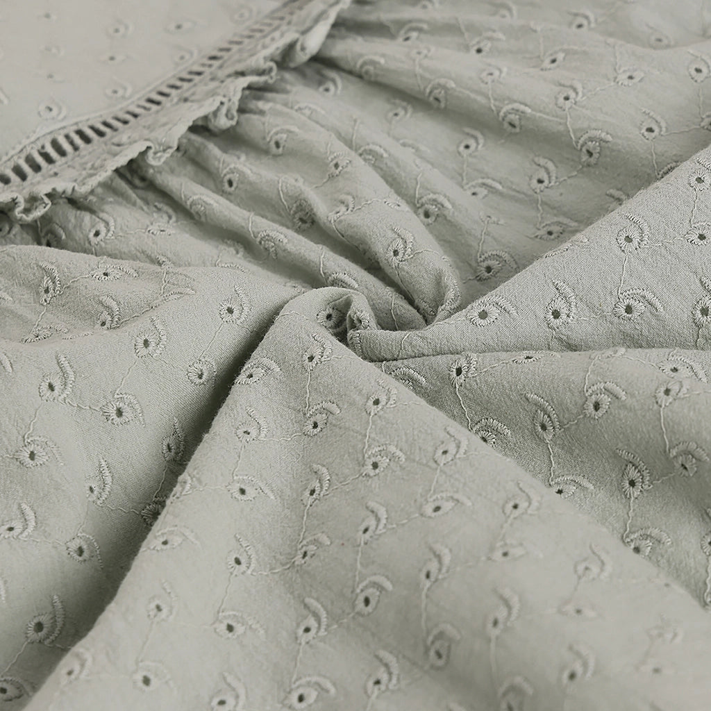 Textured fabric with floral embroidery pattern in shades of gray.