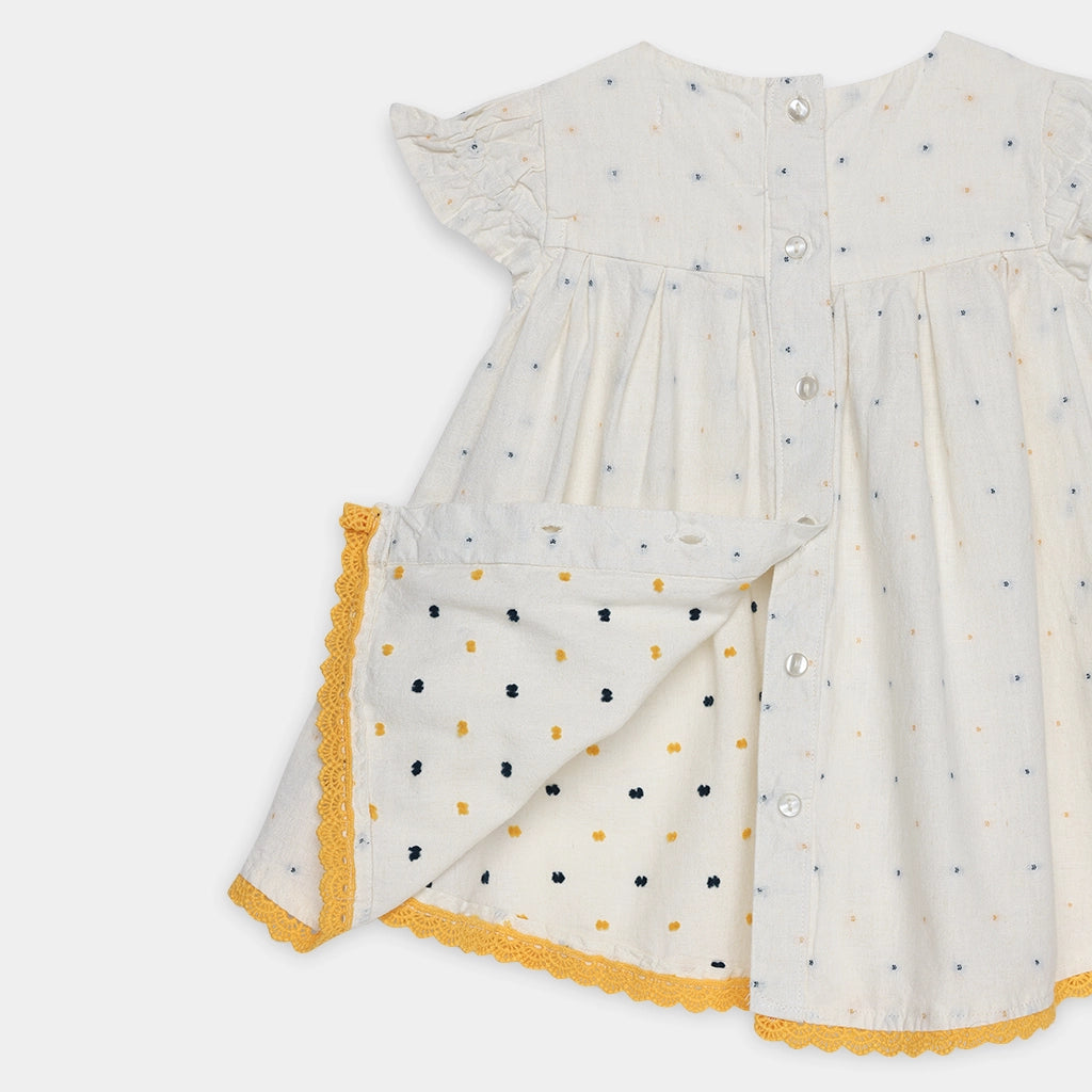 White dress with black and yellow polka dot pattern on a white background