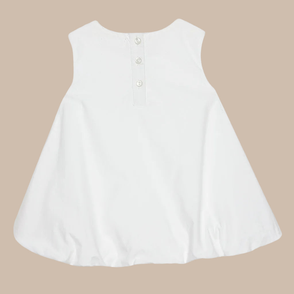 White sleeveless top with buttons on a light gray background