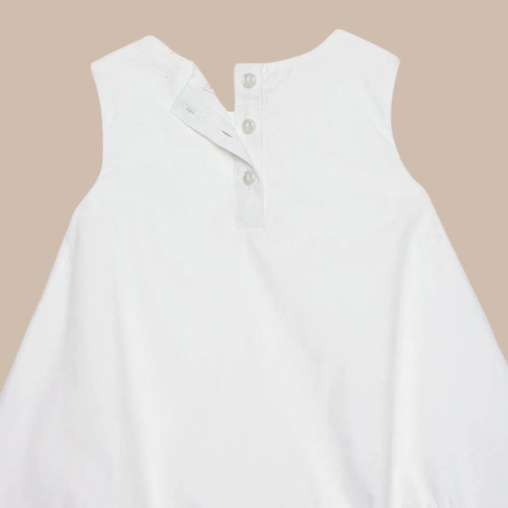 White sleeveless shirt with buttons on a light gray background