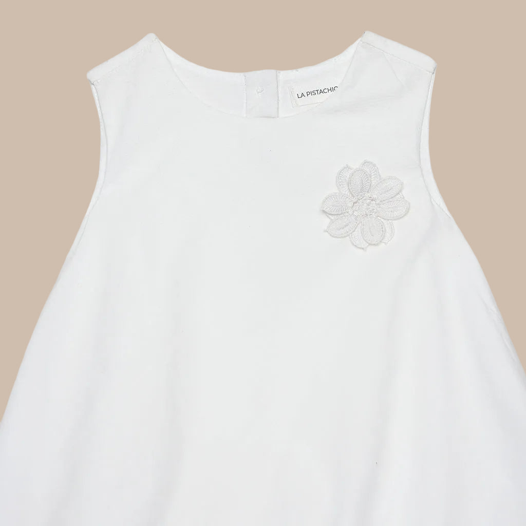 White sleeveless top with a floral embroidery detail on a white background