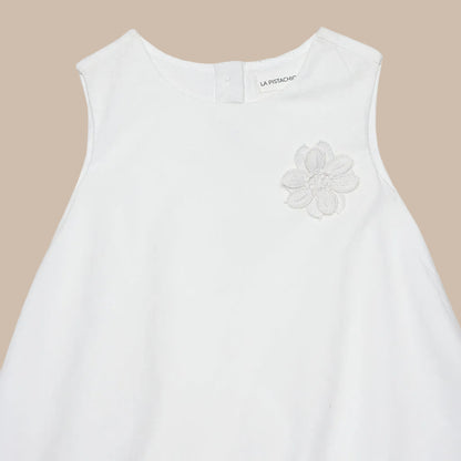 White sleeveless top with a floral embroidery detail on a white background