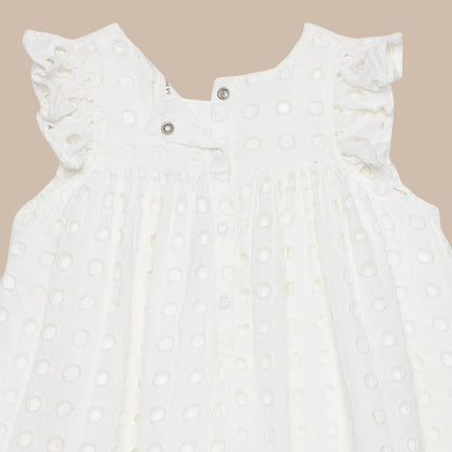 White baby romper with lace details on a light gray background