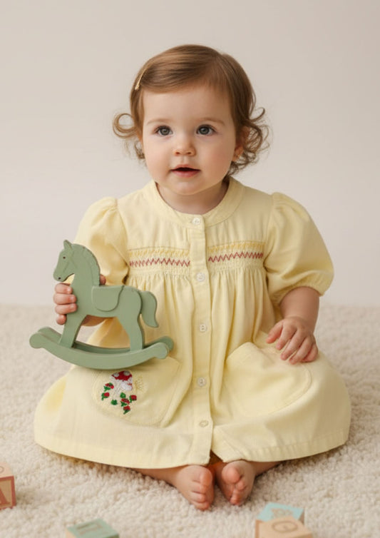 Baby girl sitting wearing buttery yellow smocked cotton A-line dress