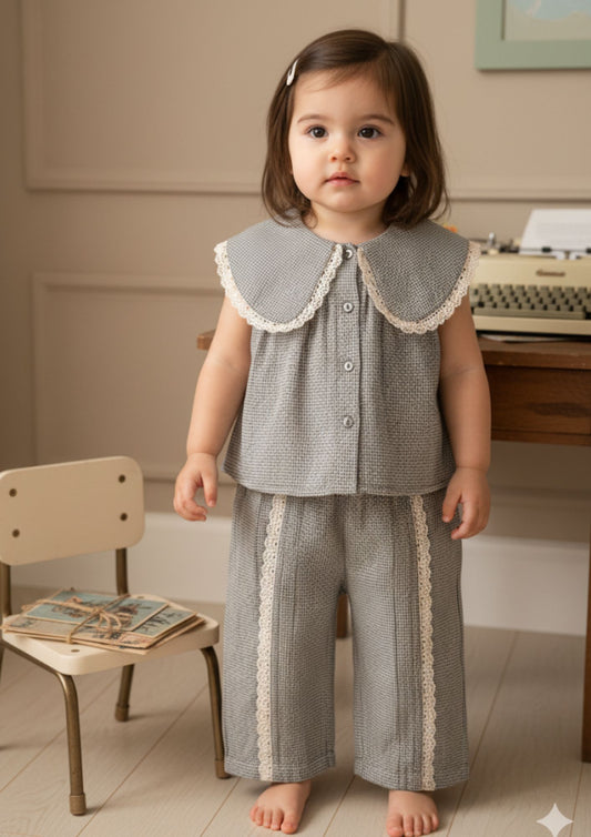 Baby girl standing wearing grey tiny checks cotton co-ord set with Peter Pan collar