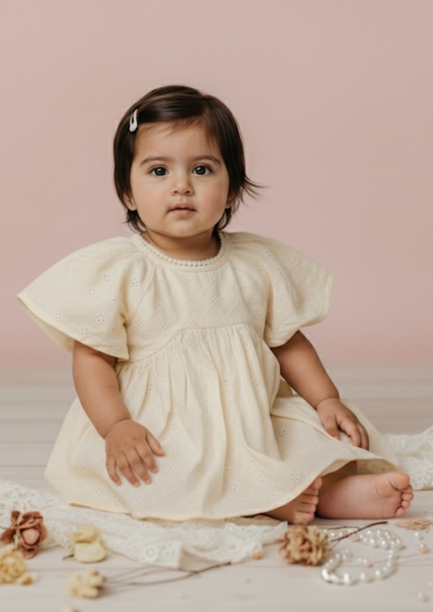 Baby girl sitting wearing ivory hakoba eyelet cotton frock