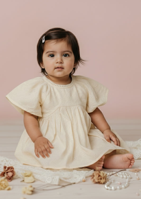Baby girl sitting wearing ivory hakoba eyelet cotton frock