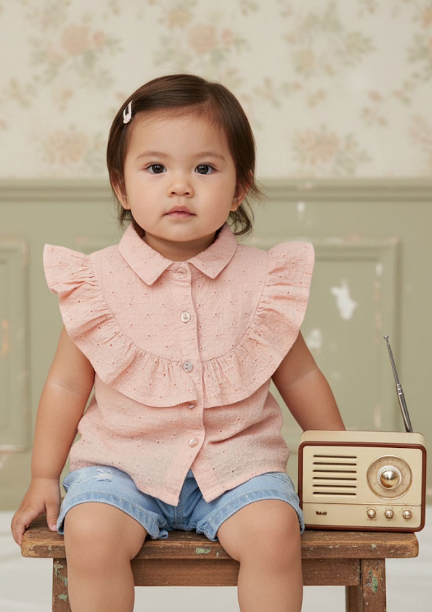 Baby girl sitting wearing peach sleeveless accoba top and light blue denim torn shorts