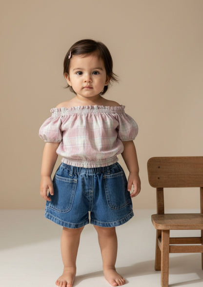 Baby girl standing wearing pink checked drop shoulder crop top and dark blue denim shorts