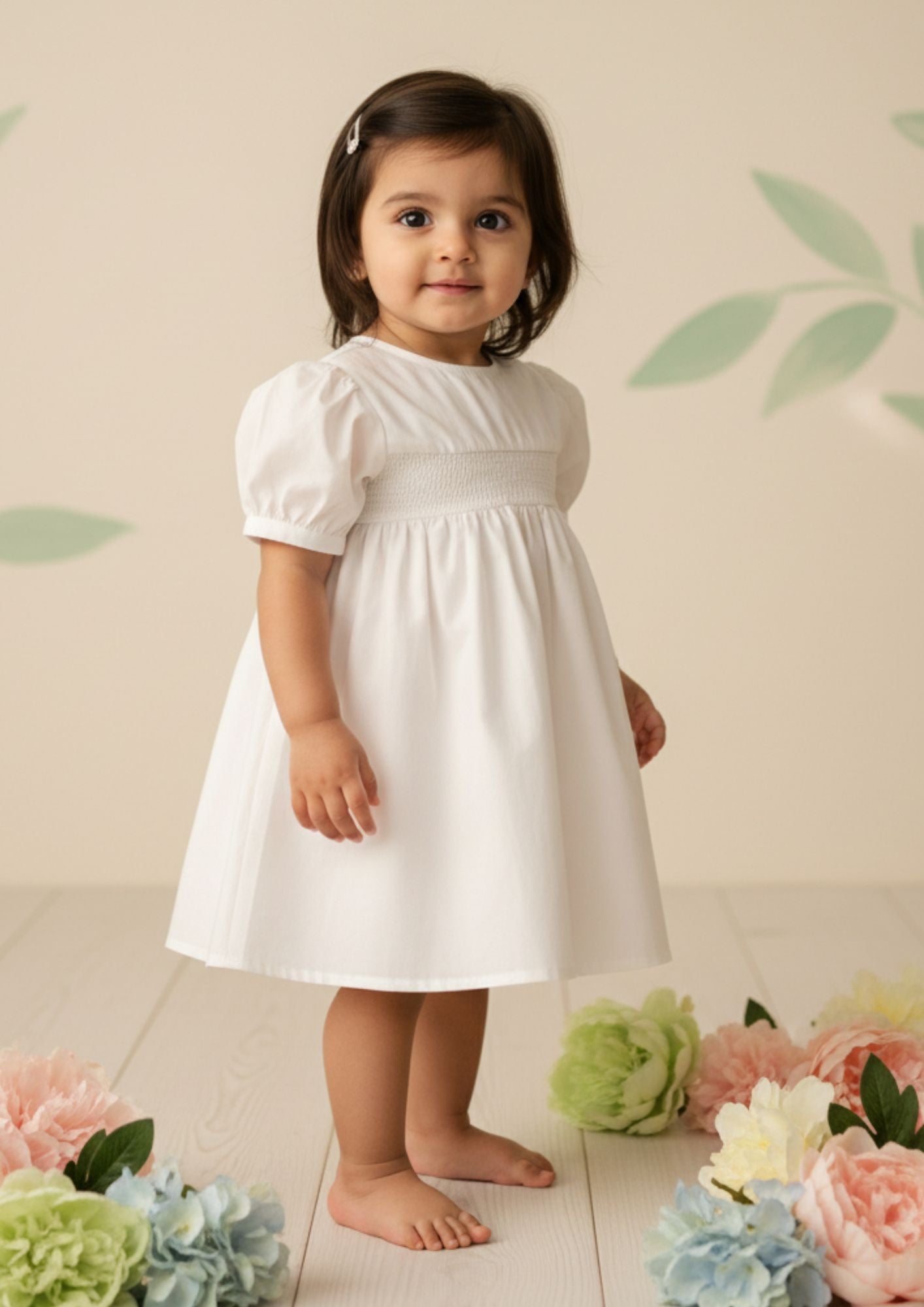 Baby girl standing sideways wearing pure white smocked cotton A-line dress